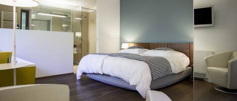 A modern hotel room with a large bed, a desk, and a chair.