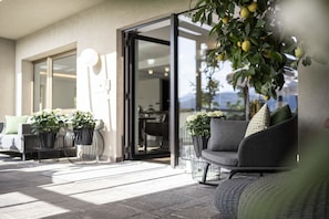 An outdoor seating area with a sofa and chairs, potted plants, and a glass door leading to an interior space. - Designhotel Gius La Residenza (Caldaro Sulla Strada del Vino)