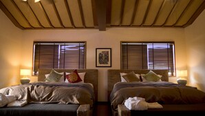 Habitación de hotel con dos camas, cabeceros de madera y un ventilador de techo.