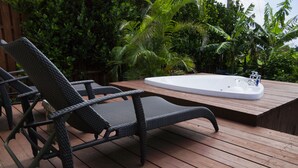 Una terraza de madera con sillones de mimbre y un jacuzzi.