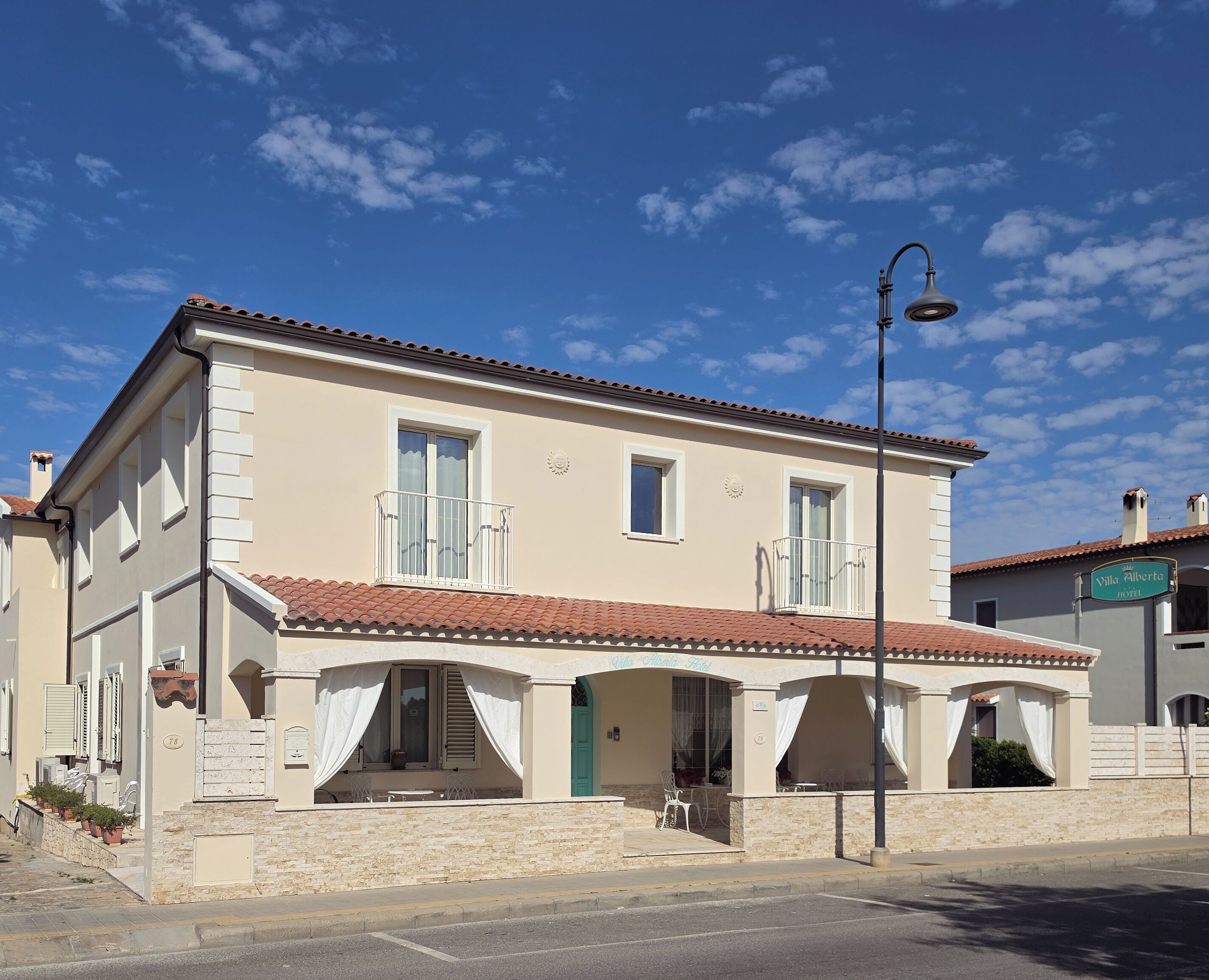 Un immeuble de deux étages doté d’un balcon, d’un lampadaire et d’une enseigne indiquant qu’il s’agit d’un hôtel.