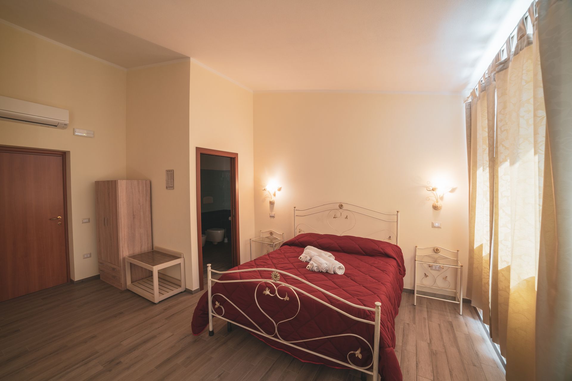 A bedroom with a bed, a wardrobe, a bedside table, and a nightstand.