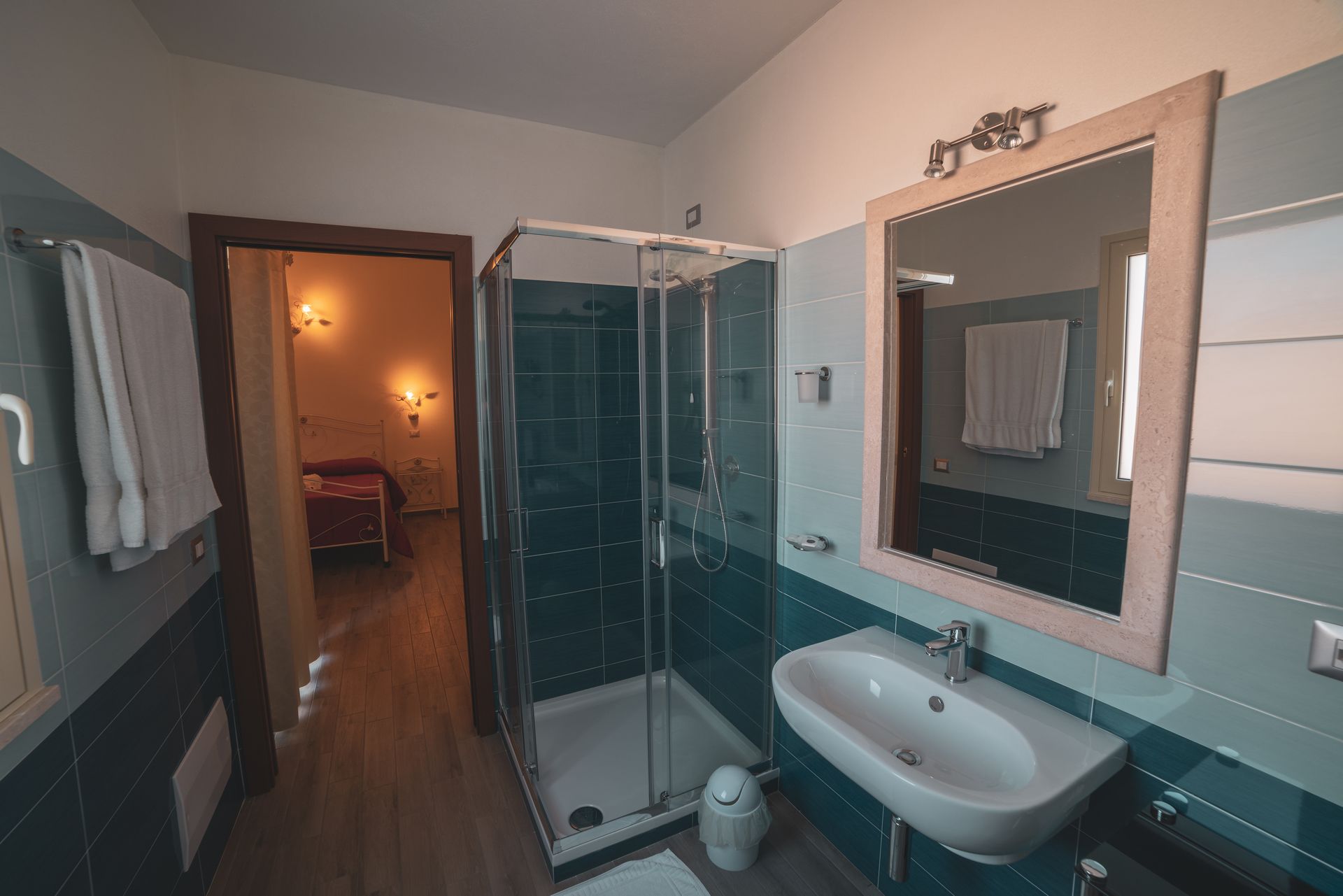 Une salle de bain moderne avec une douche à l’italienne en verre, un lavabo blanc et un grand miroir.
