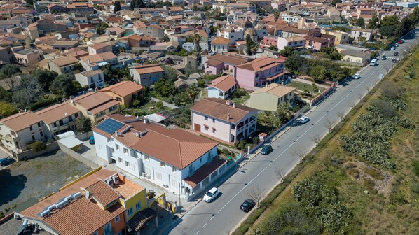 Vue aérienne d’un quartier résidentiel avec de nombreuses maisons à deux étages, une rue principale et quelques voitures garées le long de la chaussée.