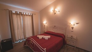Ein Schlafzimmer mit Bett, Vorhängen, Wandleuchten und einem Nachttisch.