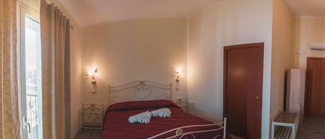 Une chambre à coucher avec un lit, deux lampes fixées au mur, une porte en bois et une petite table.