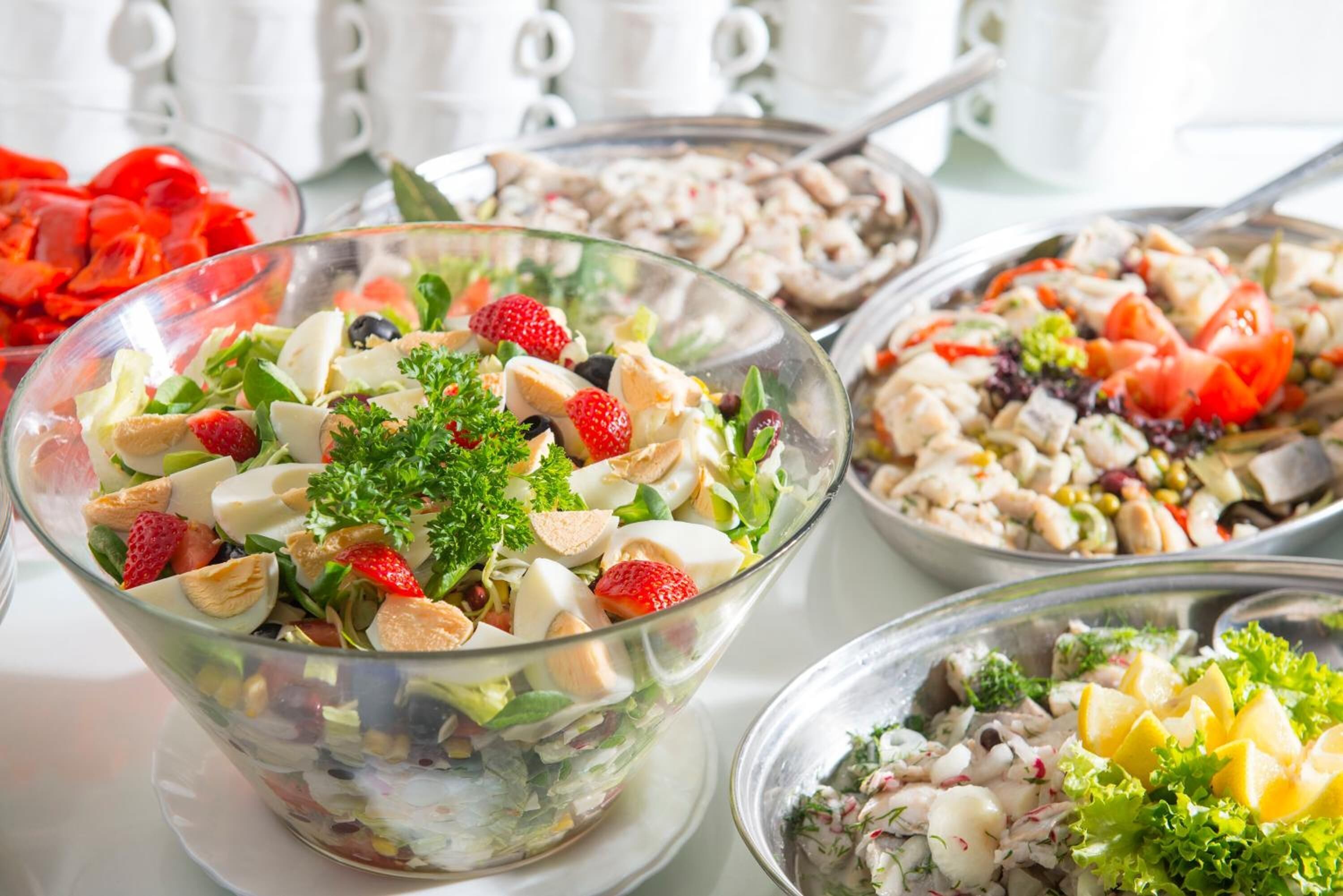 Variedad de platos de comida sobre una mesa, incluyendo una ensalada con fresas y almendras.