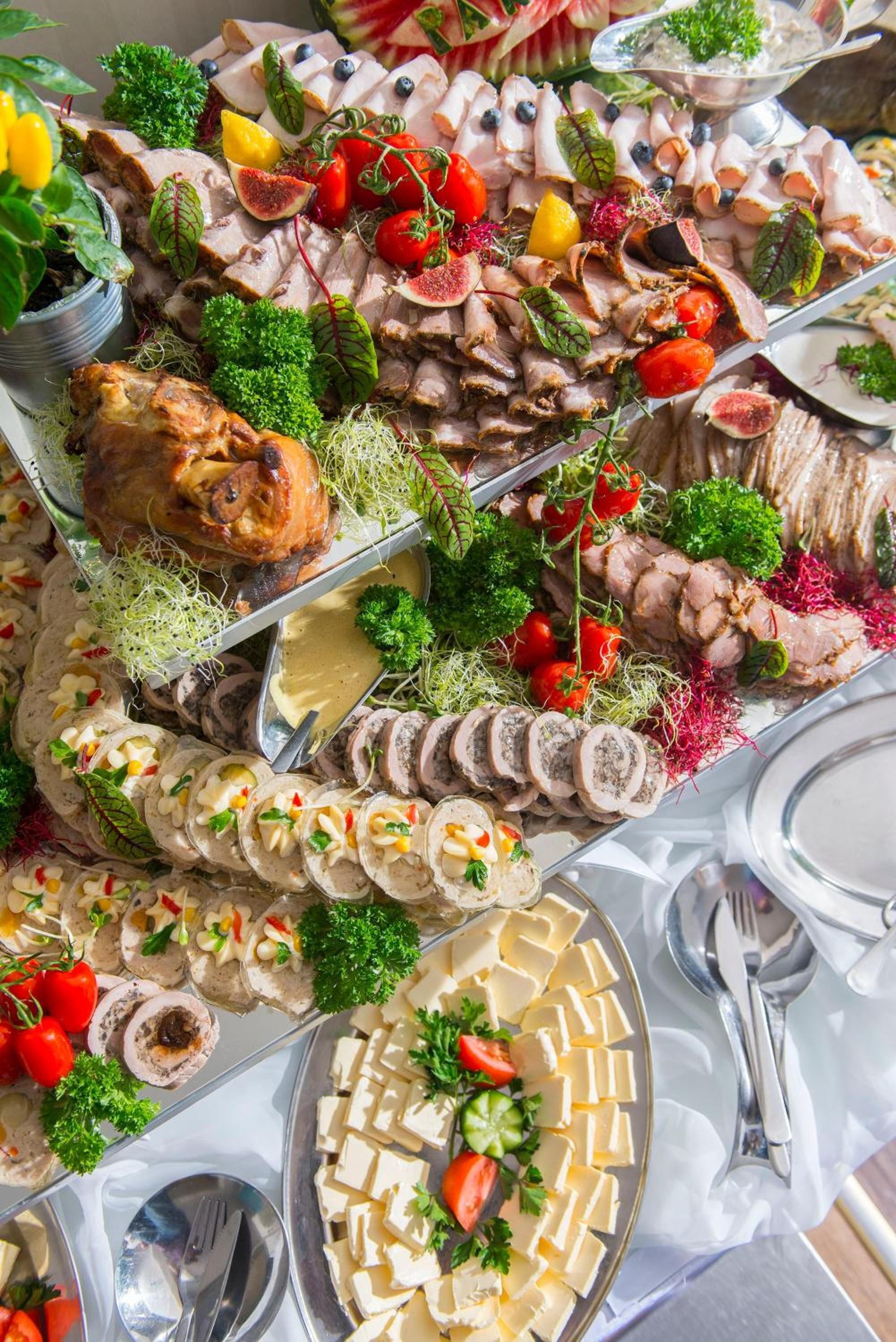 Ein reichhaltiges Buffet mit verschiedenen Speisen, darunter Fleisch, Käse und Gemüse.