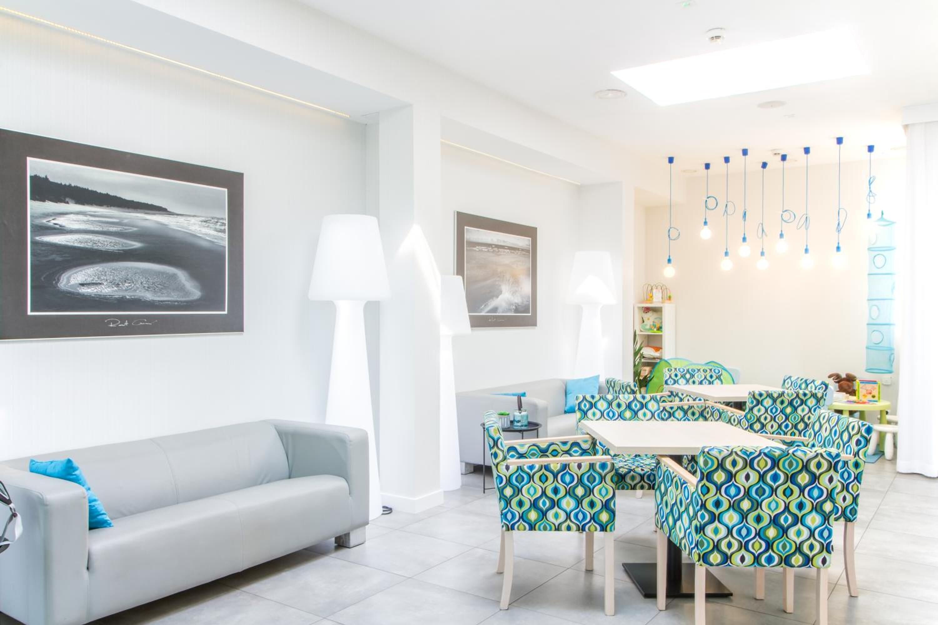 A modern living room with a grey sofa, patterned chairs, a dining table, and artwork on the walls.