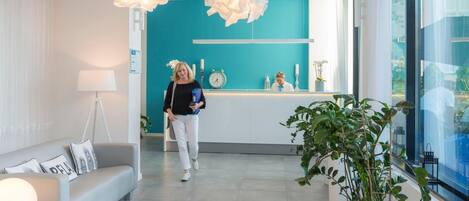 A modern reception area with a teal accent wall, a reception desk, and a large potted plant.