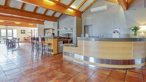 A hotel lobby with a reception desk, seating area, and a kitchen in the background. - Brit Hotel Castres (Castres)