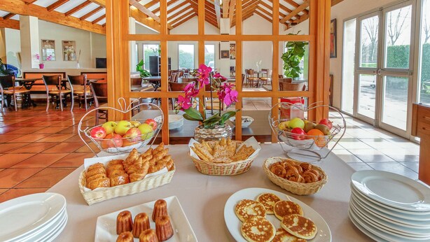 A breakfast buffet with various pastries, fruits, and bread baskets. - Brit Hotel Castres (Castres)