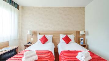 A hotel room with two beds, each with a red-striped bedspread and white pillows. There are two bedside tables with lamps, a telephone, and a small shelf with a book and a magazine.