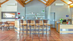 A bar area with wooden chairs, a counter, and shelves with glasses and bottles. - Brit Hotel Castres (Castres)