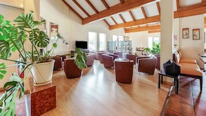 A spacious lobby with wooden beams, comfortable seating, and potted plants. - Brit Hotel Castres (Castres)
