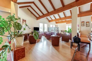 Un vestíbulo amplio con vigas de madera, asientos cómodos y plantas en macetas.