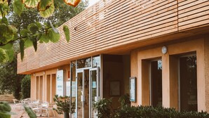 A hotel entrance with a wooden facade, glass doors, and outdoor seating. - Brit Hotel Castres (Castres)