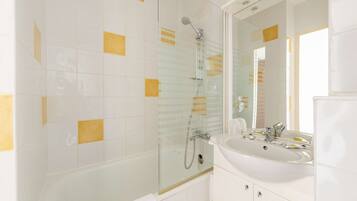 A modern bathroom with a glass-enclosed shower, a white sink, and a large mirror.