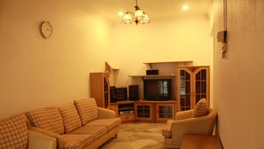 A living room with a sofa, armchair, TV, and wooden cabinet. - 32 First Island (George Town)