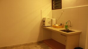 A small kitchenette with a sink, a coffee maker, and a trash bin. - 32 First Island (George Town)