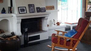 Una sala de estar acogedora con chimenea, un sillón mecedora y una mesa de madera.