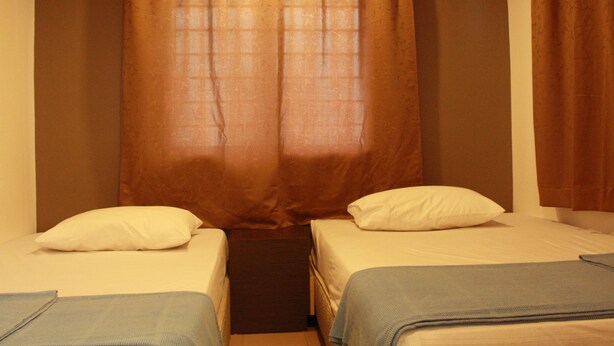 A small room with two single beds, a curtain, and a window. - 34 First Island (George Town)