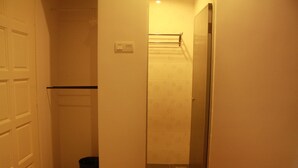 A narrow hallway with a door on the left, a trash bin, and a shower area with a towel rack. - 34 First Island (George Town)