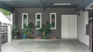 A covered outdoor area with a concrete floor, potted plants, and a white door. - 34 First Island (George Town)