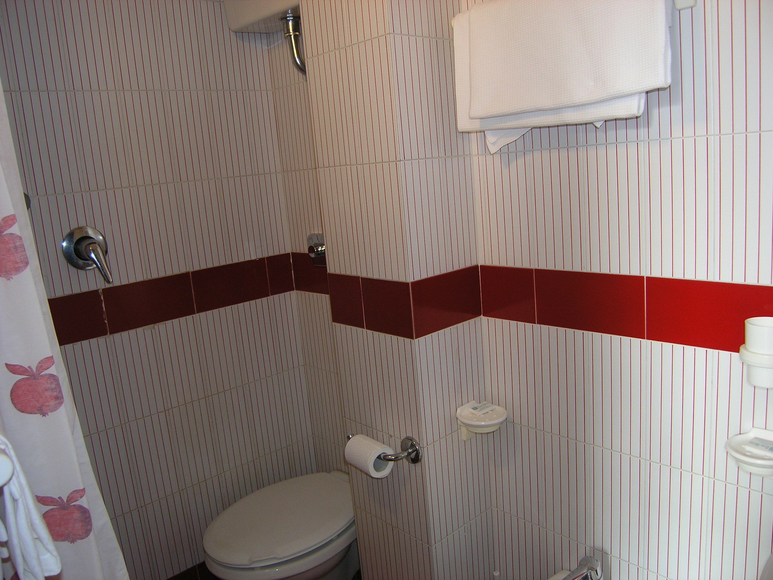 Un bagno con pareti a righe, un water, un porta asciugamani e uno spazio doccia.