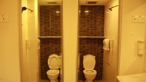 A bathroom with two toilets, a shower, and a sink.