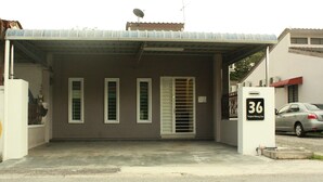 A building with a covered entrance, a sign with the number 36, and a parked car.