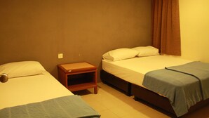 A room with two beds, a nightstand, and a brown curtain.