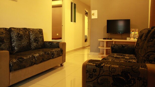 A living room with a sofa and armchair, a television, and a small table.