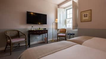 A hotel room with a bed, two chairs, a desk, a television, and a window with a view.