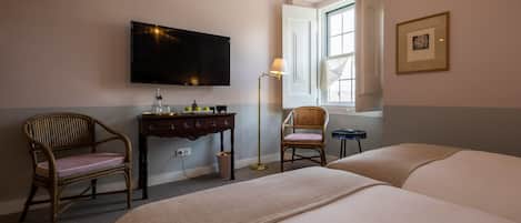 Habitación de hotel con cama, dos sillas, escritorio, televisión y ventana con vistas.