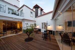Un cortile con pavimento in legno, posti a sedere all'aperto e un piccolo albero.
