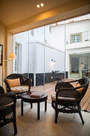 A modern interior with wicker furniture, a round table, and a large glass door leading to an outdoor area. - Pousada Vila Óbidos (Obidos)