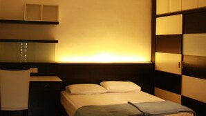 A modern bedroom with a bed, bedside table, and built-in wardrobe. - 67 First Island (George Town)