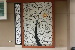 A decorative metal panel with a tree design, part of a building's exterior.