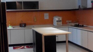 A modern kitchen with white cabinets, a black countertop, and a wooden table. - 67 First Island (George Town)