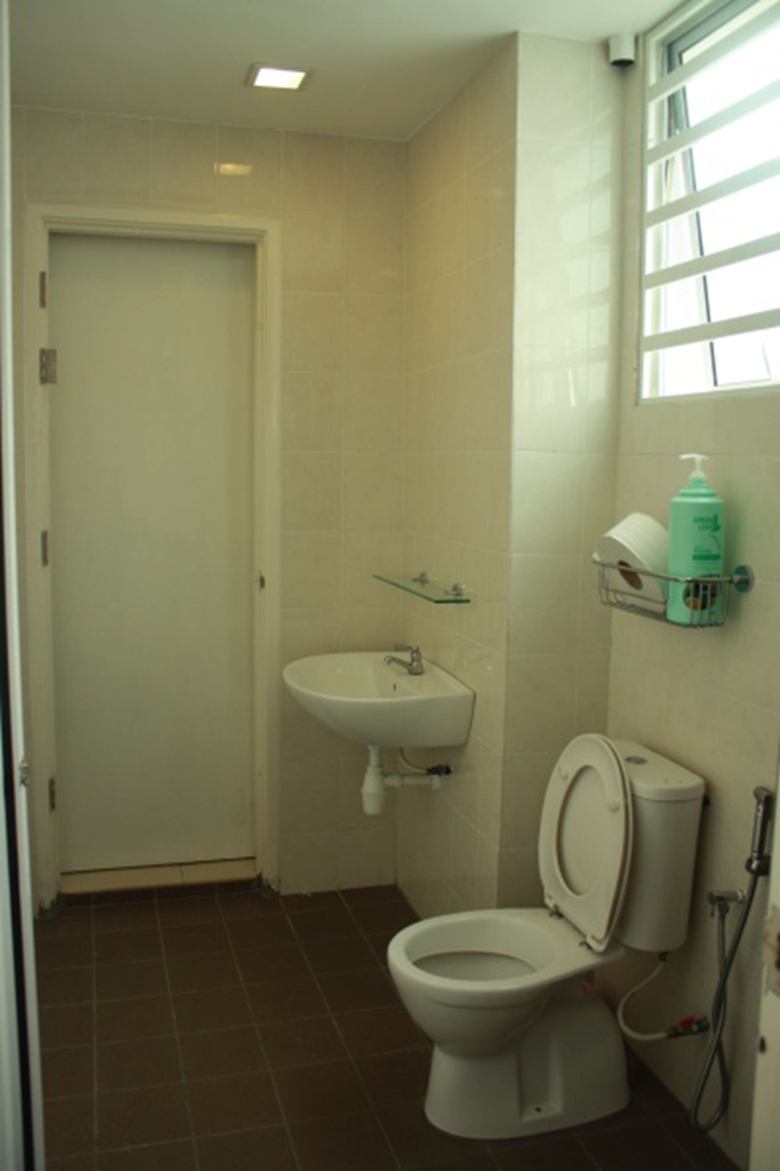 Een badkamer met toilet, wastafel en een raam met zonwering.