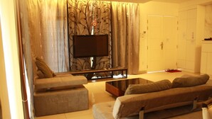 A living room with a sofa set, a flat-screen TV, and a decorative wall piece. - 67 First Island (George Town)