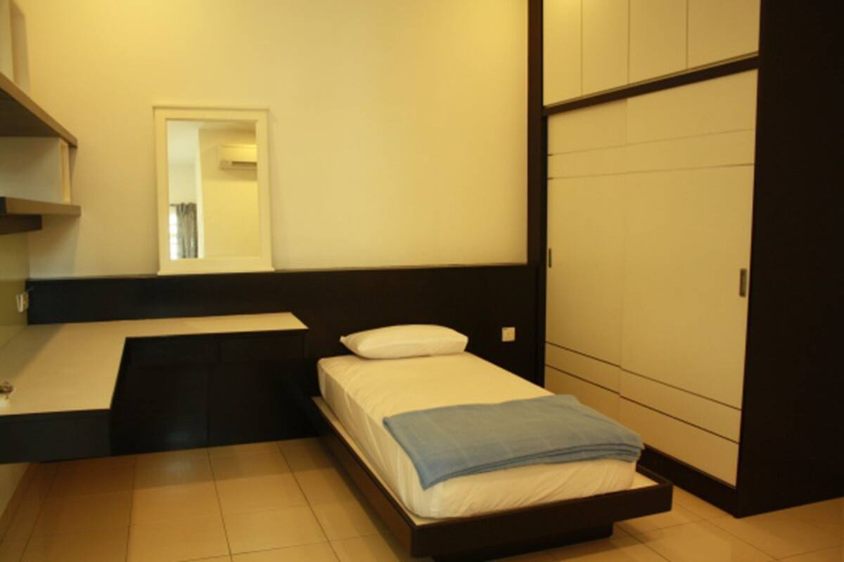Un dormitorio con cama, mesita de noche, espejo y armario.