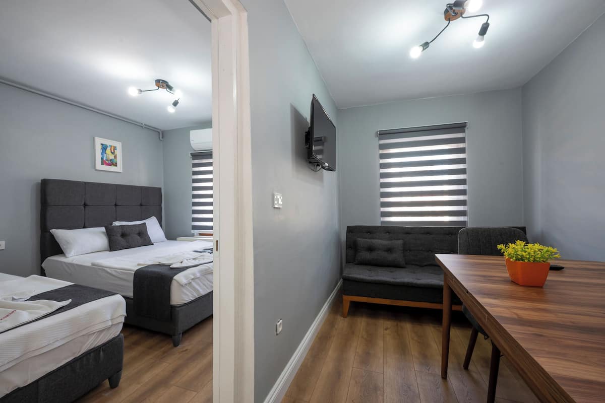 A modern room with a bed, a sofa, a dining table, and a TV mounted on the wall.