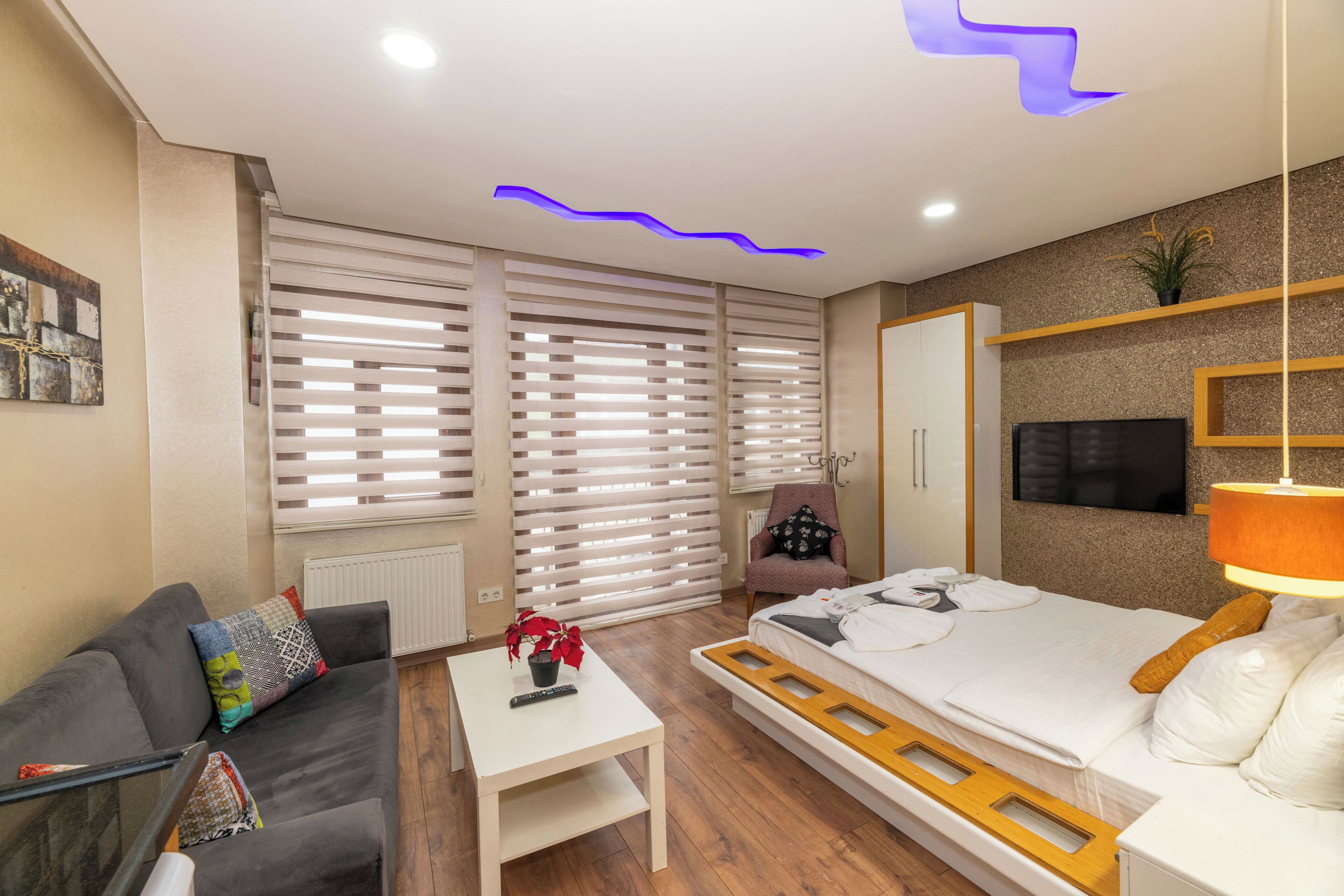 A modern hotel room with a sofa, a bed, a small table, and a TV.