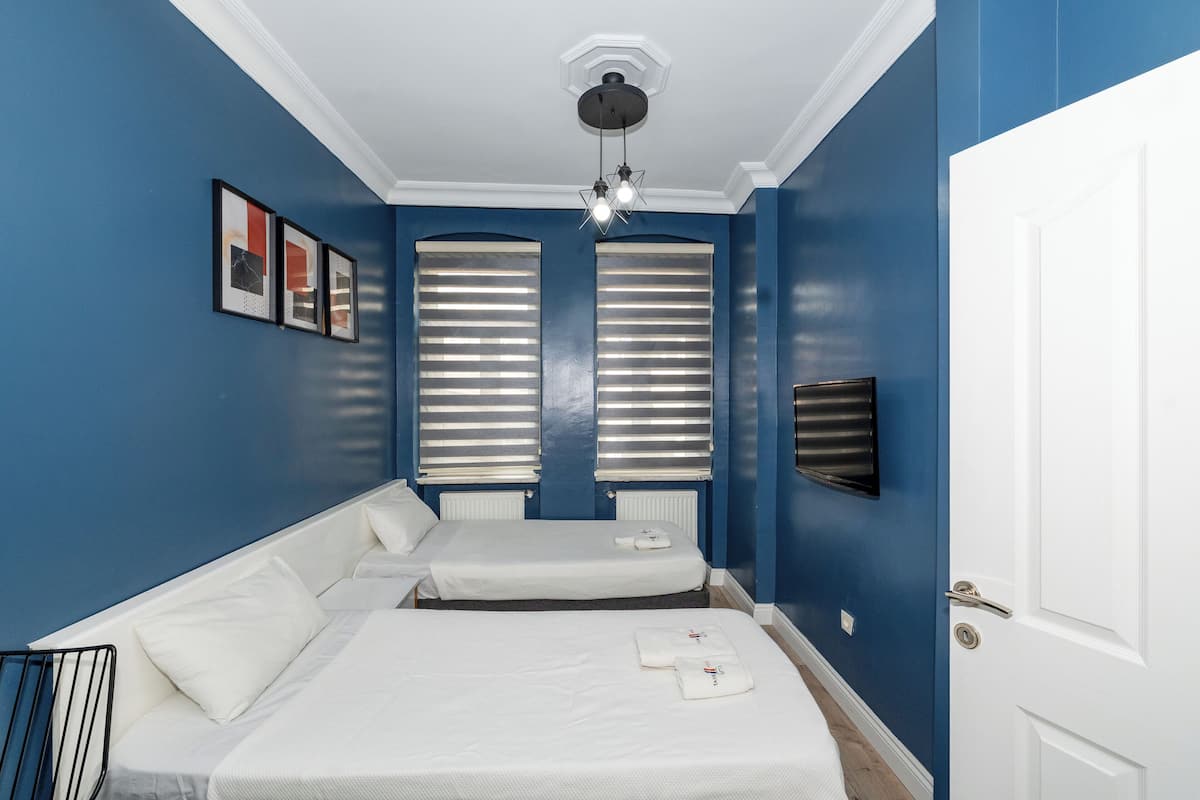 A room with two beds, a white door, and a ceiling light fixture.