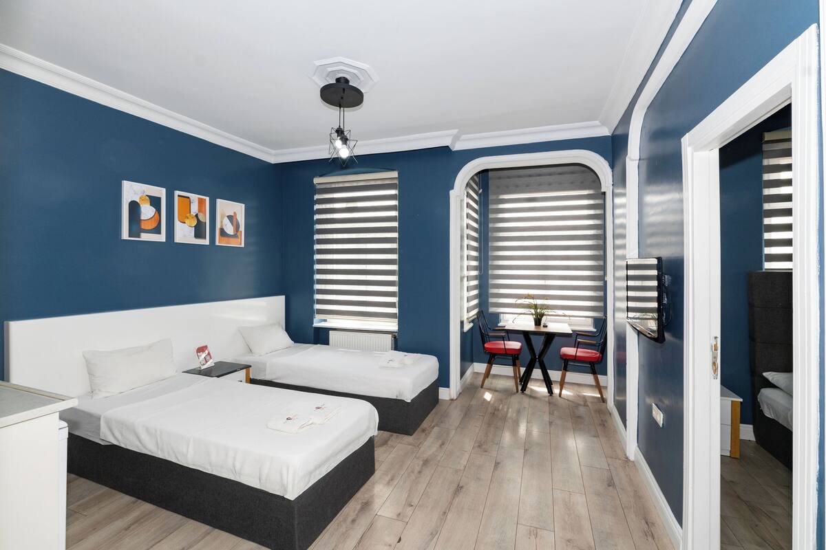 A bedroom with two beds, a desk, and a TV.