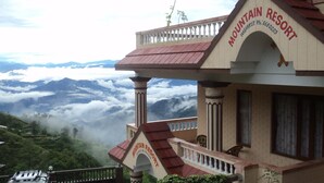 A mountain resort building with a balcony and a view of the surrounding mountains and clouds. - Mountain Resort (Baluwapati Deupur)