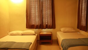 A room with two single beds, a small wooden nightstand, and a window with curtains. - 02 First Island (George Town)