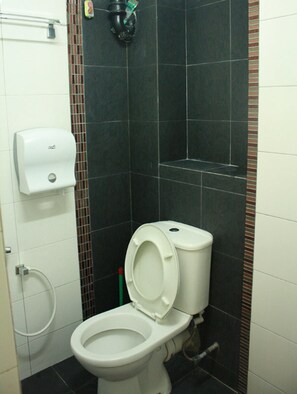 A small bathroom with a white toilet, a hand dryer, and a toilet paper dispenser. - 02 First Island (George Town)